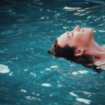 Woman floating in calm water, viewed from above, evoking the stillness associated with meditative swimming