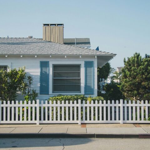 Neritic - A light, coastal-inspired living room featuring natural wood textures, soft blue accents, woven décor, and ocean-influenced artwork.