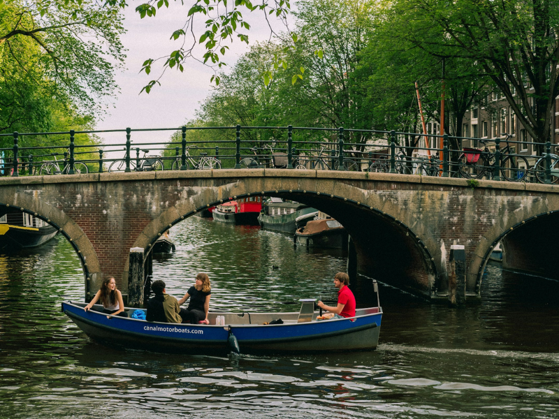 People ride a boat through a calm canalway, reflecting Water’s Quiet Presence in everyday motion. Photo by Alexandra Lazarevskaya.