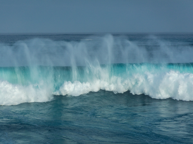 Breaking 2-meter coastal wave demonstrating ocean energy potential, with each wave containing energy comparable to a gallon of gasoline.