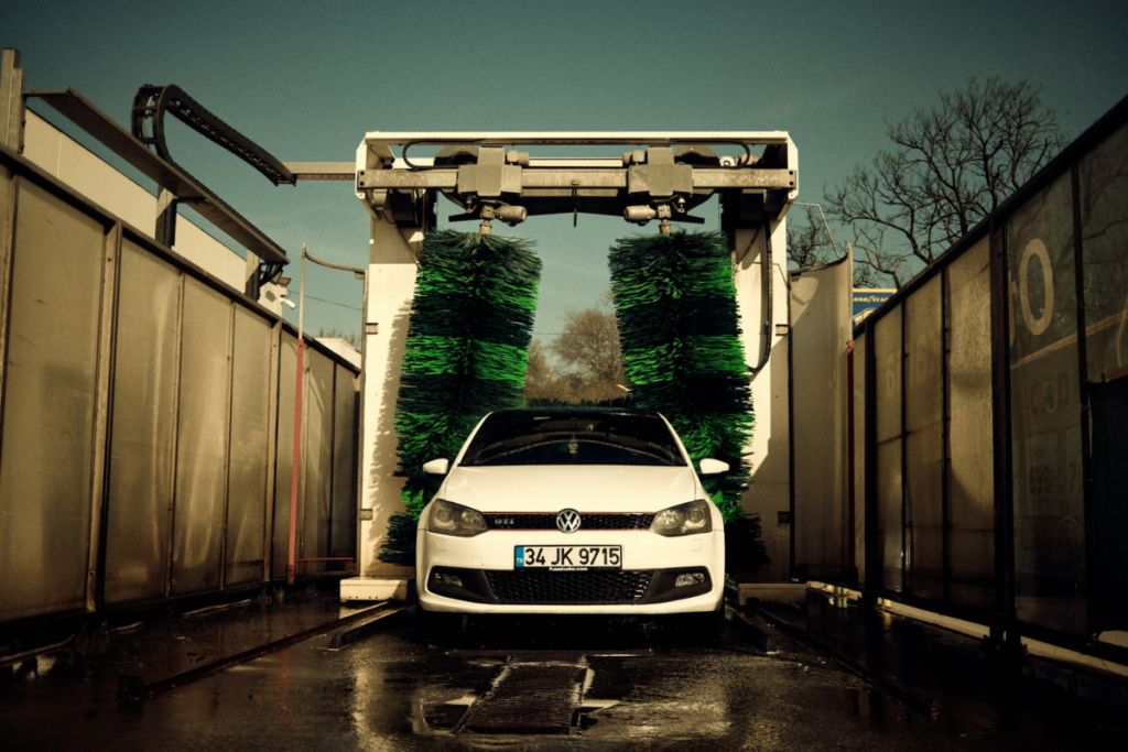 White car parked at a car wash during washing a car with water process