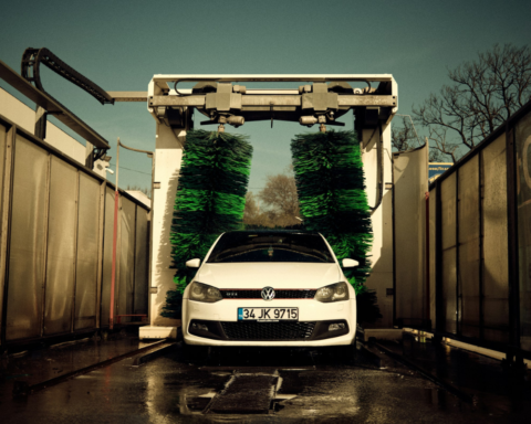 White car parked at a car wash during washing a car with water process