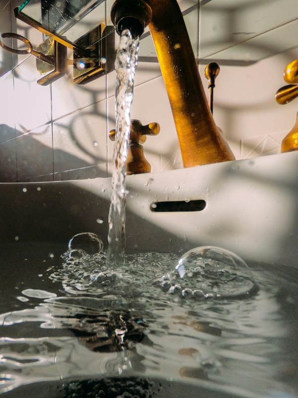 water splash on brown wooden stick illustrating the natural movement of spring water vs. purified water and the contrast between organic sources and controlled systems