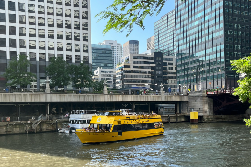 Yellow water taxis traveling down a river beside tall city buildings, illustrating urban waterfront transport and modern water taxis.