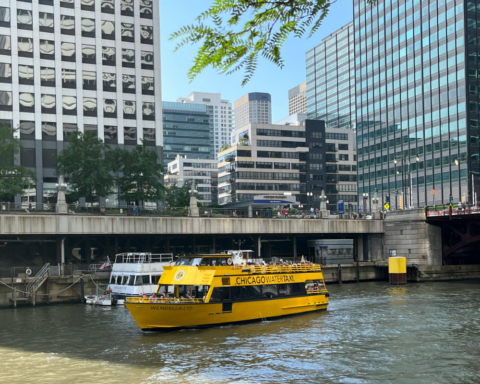 Yellow water taxis traveling down a river beside tall city buildings, illustrating urban waterfront transport and modern water taxis.