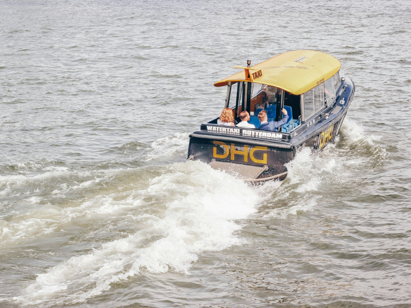 Blue and yellow speedboat moving across a body of water, illustrating modern water taxis used for fast passenger transport along coastal and urban waterways.