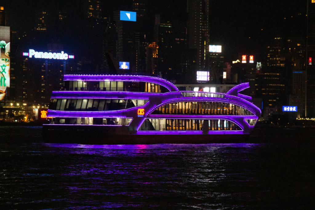 Lighted river cruise sailing at night with city lights reflecting on the water, illustrating the nighttime experience of river cruises.