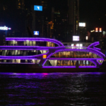 Lighted river cruise sailing at night with city lights reflecting on the water, illustrating the nighttime experience of river cruises.