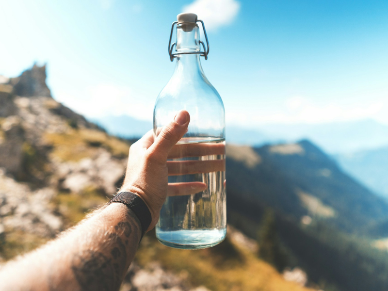 How Long Can You Survive Without Water? A person holding an empty clear glass bottle, illustrating water scarcity and the risks of dehydration.