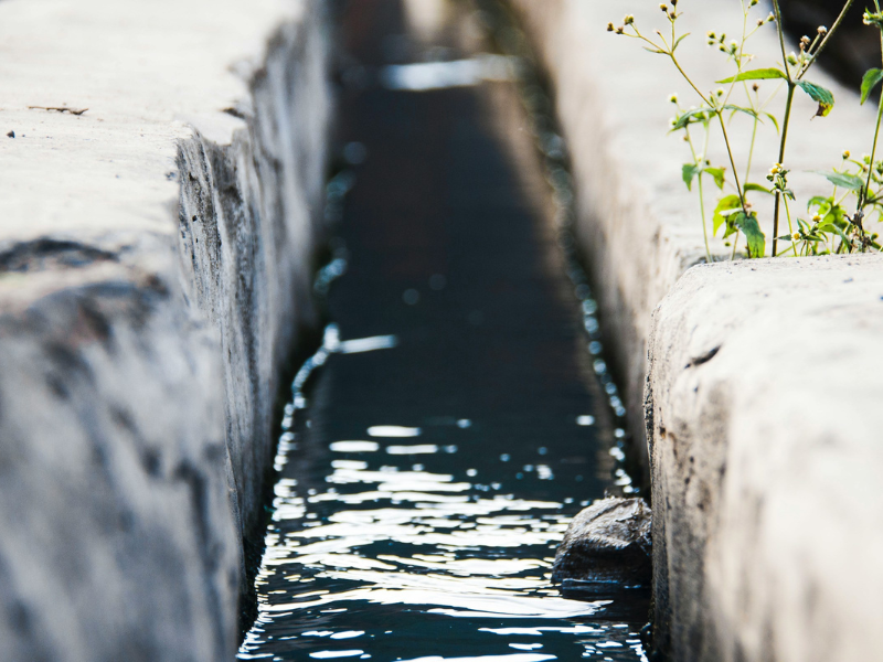 Gray concrete bridge over water affected by water pollution in an urban environment