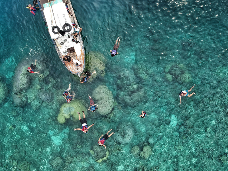 People swimming near a boat while enjoying water sports activities in open water
