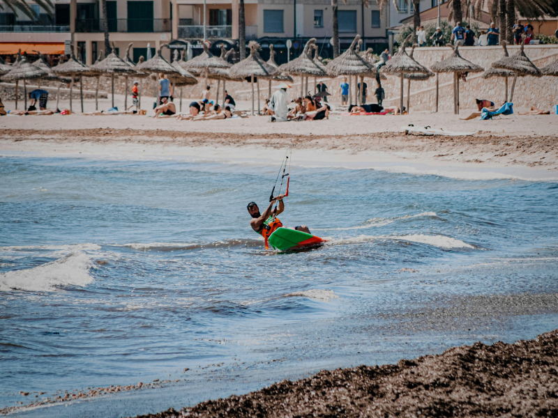 Man in a red shirt riding a red kayak across the sea during daytime water sports activity