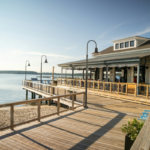 Wooden boardwalk and waterfront building beside a calm tidal park, showcasing a coastal space designed to adapt to changing tides and reconnect people with nature.