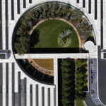 Aerial view of a modern building featuring a circular blue-green roof with lush vegetation, trees, and open green space integrated into the rooftop design.Blue-green roofs transform urban rooftops into living landscapes, managing stormwater while creating greener, more resilient cities.
