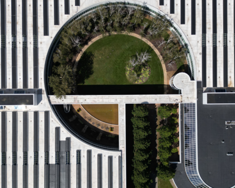 Aerial view of a modern building featuring a circular blue-green roof with lush vegetation, trees, and open green space integrated into the rooftop design.Blue-green roofs transform urban rooftops into living landscapes, managing stormwater while creating greener, more resilient cities.
