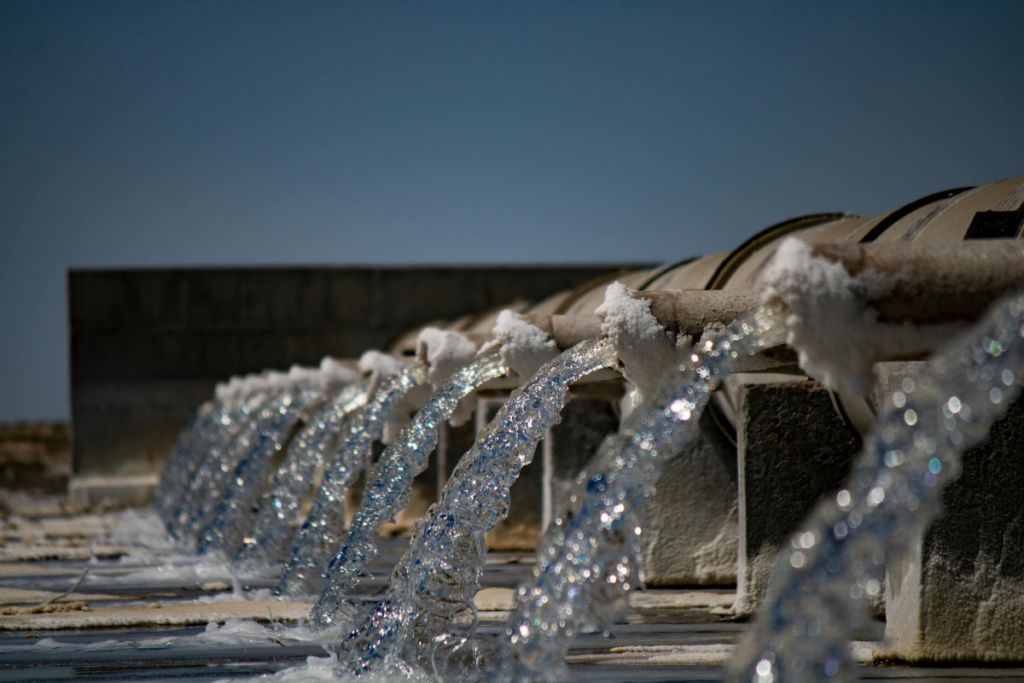 Water reuse facility with treated water flowing from multiple discharge pipes, illustrating wastewater recycling and sustainable water management.
