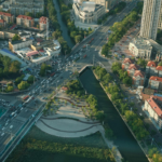 Aerial view of an urban landscape with a canal, green corridors, and surrounding infrastructure, illustrating how sponge cities and wetlands can improve stormwater management and climate resilience.