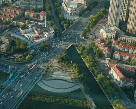 Aerial view of an urban landscape with a canal, green corridors, and surrounding infrastructure, illustrating how sponge cities and wetlands can improve stormwater management and climate resilience.