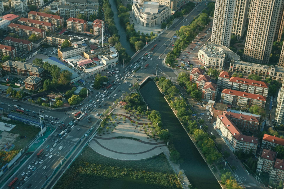 Aerial view of an urban landscape with a canal, green corridors, and surrounding infrastructure, illustrating how sponge cities and wetlands can improve stormwater management and climate resilience.