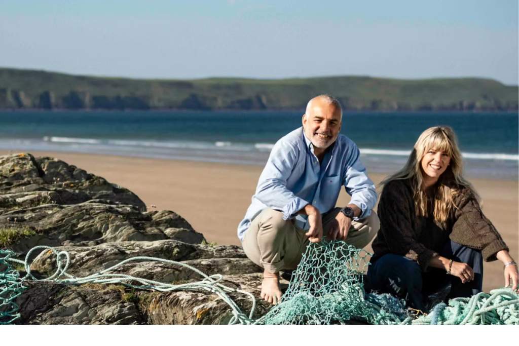 Ecotribo founders beside reclaimed fishing nets on a coastline, highlighting how recycled ocean plastic supports coastal communities, local manufacturing, and ocean stewardship.