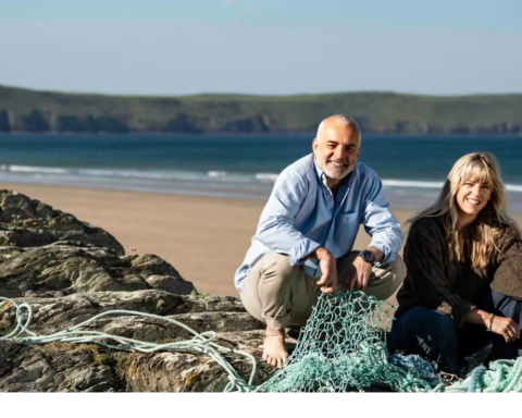 Ecotribo founders beside reclaimed fishing nets on a coastline, highlighting how recycled ocean plastic supports coastal communities, local manufacturing, and ocean stewardship.