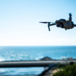A drone flying above the ocean near a coastal bridge, demonstrating the use of drones for ocean observation, coastal monitoring, and marine research.