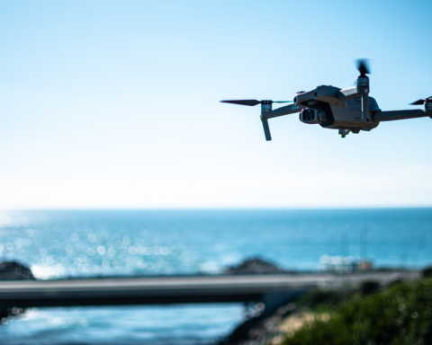 A drone flying above the ocean near a coastal bridge, demonstrating the use of drones for ocean observation, coastal monitoring, and marine research.