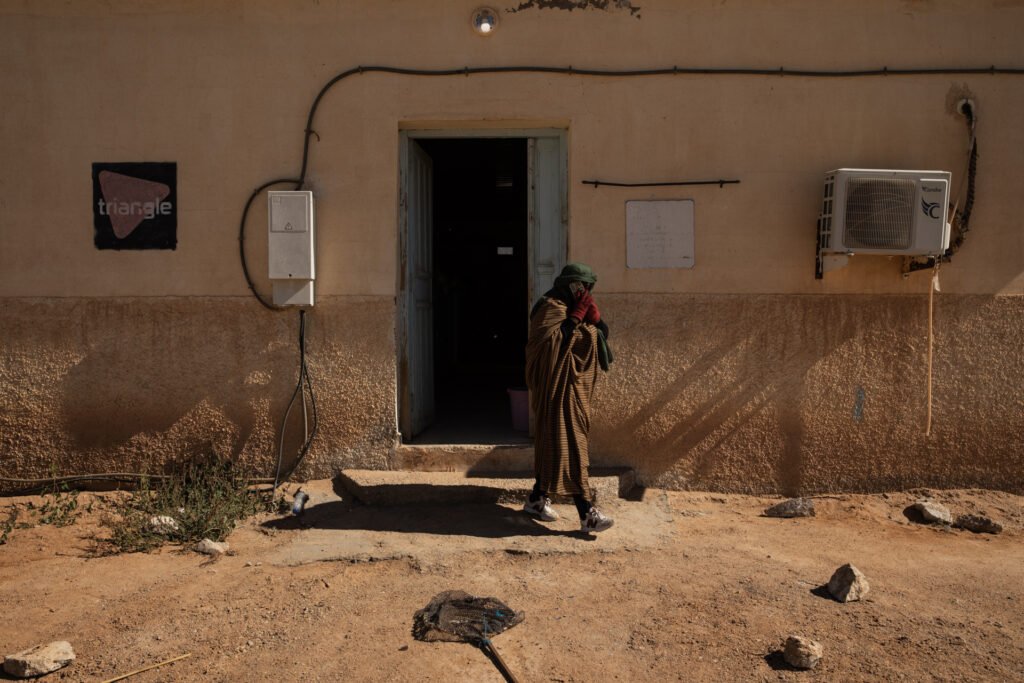 Worker stepping outside the N’khaila fish farm into the desert landscape.