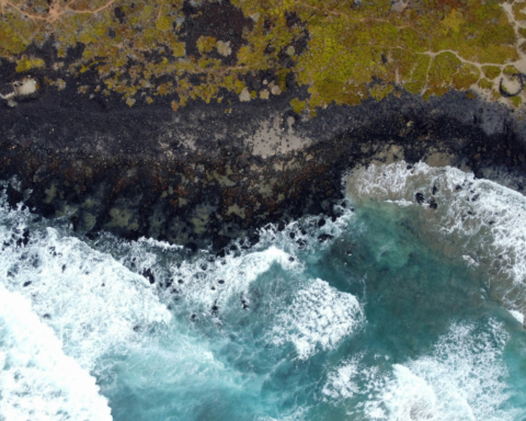 Aerial view of ocean waves meeting a rocky coastline, showing how the tide shapes the shores of coastal islands.