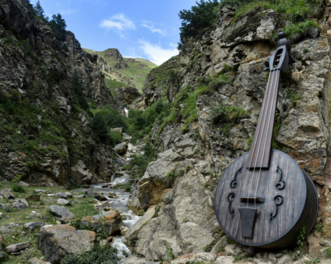 : Large string instrument beside a rocky mountain stream, representing the connection between music, nature and river soundscapes.
