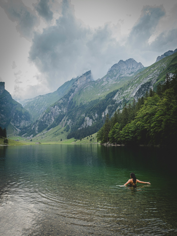 A swimmer enjoys a peaceful mountain lake, highlighting how even crystal-clear waters require proper monitoring to ensure safety from harmful algal blooms.