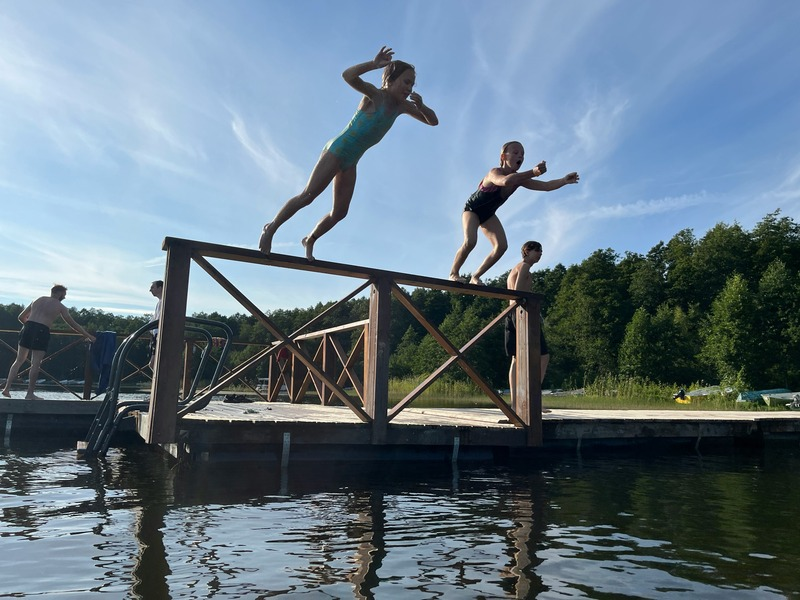 Children enjoying a summer swim in a lake, highlighting the importance of monitoring water quality and harmful algal blooms to ensure safe freshwater recreation.